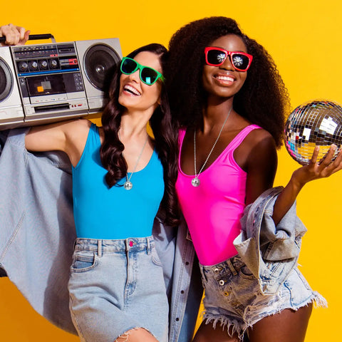 Two women with 70s vibe wearing Mirror Disco Ball Necklaces Set Of 20 Silver Hanging Ornaments For 70s Party, holding boombox and disco ball.