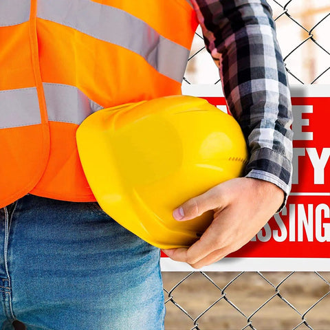 Close-up of person holding yellow hard hat near Private Property No Trespassing Signs 9x12 Inches Weatherproof And Water Resistant 4 Pack