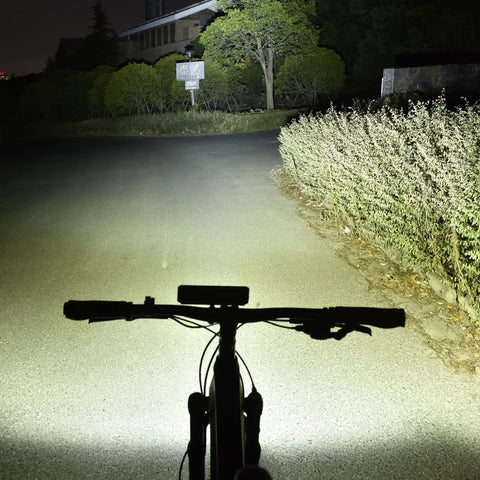 Ultra Bright USB Rechargeable Bike Light With 1400 Lumens illuminating a dark road from bicycle handlebar view.
