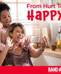 Mother and daughter smiling and taking a selfie in a kitchen, with the text 'From Hurt To Happy' and Band-Aid logo visible.