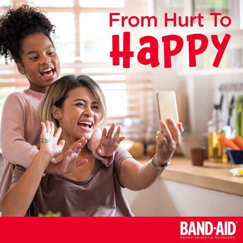 Mother and daughter smiling and taking a selfie in a kitchen, with the text 'From Hurt To Happy' and Band-Aid logo visible.