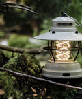 Outpost Lantern With Helix Edison Rope in vintage white, set in a forest setting, highlighting steel body and nostalgic glow.