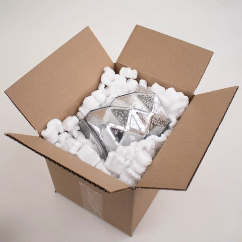 Heavy Duty White Packing Peanuts For Zero Stress Shipping Anti Static S Curve Half Cubic Foot Void Fill cushioning a shiny object in a cardboard box.
