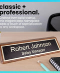 Personalized Walnut Wood Desk Name Plate With Black Base And Gold Lettering, 2 By 8 Inches on desk with chair, pen, and notebook