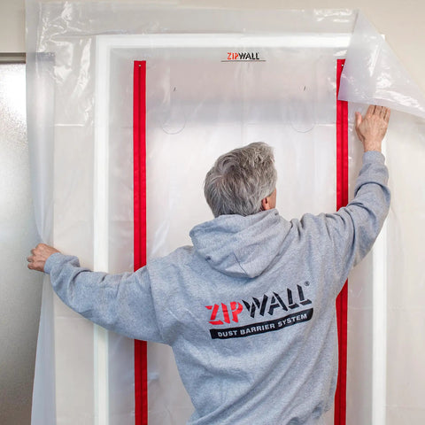 Man installing Red ZipDoor Kit For Dust Protection In Remodeling Jobs Pro Grade Flame Retardant Plastic Door Cover With Preinstalled Zippers