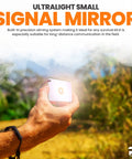 Hand holding signaling mirror from Rugged 5-In-1 Glow-In-The-Dark Fire Starter Kit with Compass in outdoor setting.
