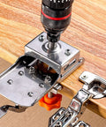 Angled view of metal 35mm hinge boring drill guide with orange knob mounted on wood edge