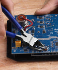 Using Six Piece Wire Cutters Set With Six Inch Precision Flush Cutters for precise wire cutting on a circuit board.