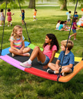 Children sitting on 700 Pound Capacity Giant 60 Inch Skycurve Platform Tree Swing For Kids And Adults With Two Hanging Straps Rainbow Patented Design