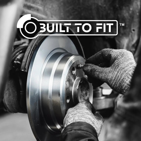 Rear brake rotor being installed on wheel hub; silver metal, close-up with gloved hands.