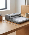 Office desk with Binding Machine Locating Pin And Metal Punch Alignment Peg beside document binder