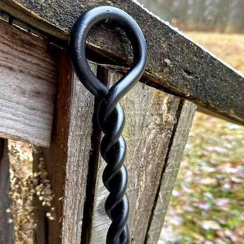 Close-up of 40 Inch Fire Poker For Fire Pit With Twisted Rope Handle in black steel against wood background