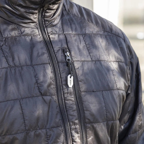 Close-up of ceramic striker fire starter kit zirconia stone hanging from black jacket zipper