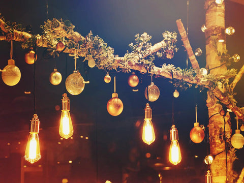 Decorative lights and ornaments hanging from a branch, creating a warm festive atmosphere.