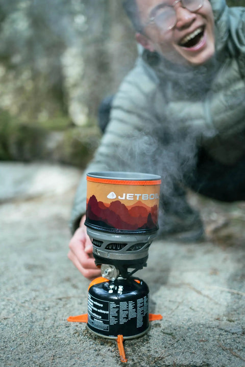 MiniMo Camping And Backpacking Stove Cooking System With FluxRing Technology in use outdoors, steam rising, adjustable heat control shown.
