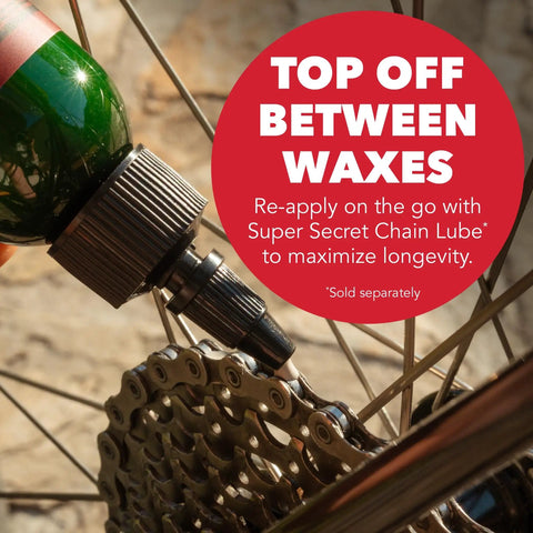 Close-up of a bicycle chain being lubricated with a green bottle, highlighting the message 'Top Off Between Waxes'.