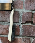 Four-Piece Shoe-Handle Wire Scratch Brush Set With Black Oil-Tempered Steel Bristles hanging on a brick wall