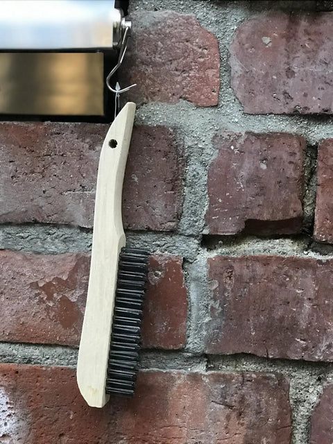 Four-Piece Shoe-Handle Wire Scratch Brush Set With Black Oil-Tempered Steel Bristles hanging on a brick wall