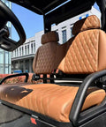 Pro Grade Two Passenger Electric Golf Cart Featuring Fast Charge Lithium Battery And Slick Aluminum Frame seating interior with quilted brown cushions.