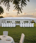 Built Tough 10 By 30 Foot Heavy Duty Outdoor Wedding Canopy With Eight Sidewalls Offering Full Uv Protection And Being Totally Waterproof Perfect For Your Backyard Parties And Big Events set up in a garden with dining tables and chairs