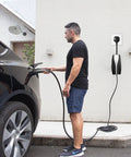 Man using Road Trip Ready Nema 14 To 50 Ev Charger Adapter For Tesla Gen 2 Mobile Unit 32 Amp Level 2, black extension cable.