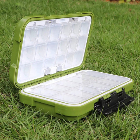 Open green floating double sided fishing tackle box with adjustable dividers, showing several compartments on grass