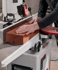 Operator using Six Inch Long Bed Jointer Featuring Helical Cutterhead And 27 Carbide Inserts for wood jointing.