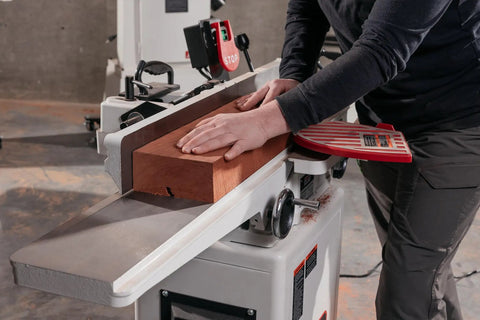 Operator using Six Inch Long Bed Jointer Featuring Helical Cutterhead And 27 Carbide Inserts for wood jointing.
