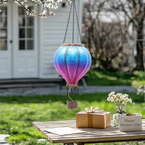 Blue Purple Hot Air Balloon Solar Lantern for garden decor hanging outdoors, flickering flame effect, above table with gift and flowers