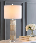 Champagne Glass and Crystal Table Lamp With White Faux Silk Drum Shade in living room setting, emphasizing cozy vibe.
