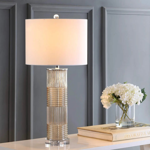 Champagne Glass and Crystal Table Lamp With White Faux Silk Drum Shade in living room setting, emphasizing cozy vibe.
