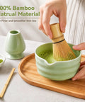 Complete Five Piece Matcha Making Kit With Bamboo Whisk Chasen stirring matcha in ceramic bowl on bamboo tray