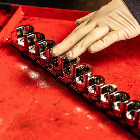 Gloved hand arranging Three Eighth Inch Drive Weatherhead Socket Master Set 13 Piece SAE Sockets on a plastic rail