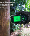 Pin Type Wood Moisture Meter With Hold Function 12mm Probes Big Backlit LCD Screen And Three Color LED Bar Graph For Easy Accurate Wood Moisture Readouts Ideal For DIY Carpentry And Home Renovation Projects. Held on tree trunk outdoors