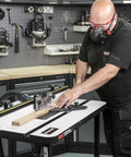 Woodworker using Rock Solid Free Standing Router Table With Heavy Duty Steel Base And Spacious 24 By 16 Inch Laminated Top.
