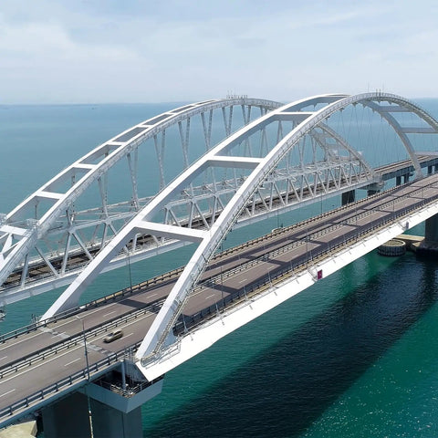 Aerial view of a modern cable-stayed bridge spanning over blue water on a clear day.