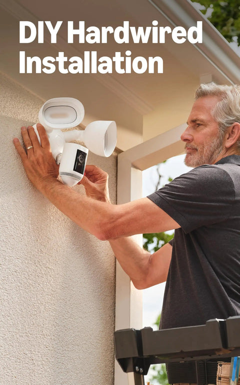 Person installing Floodlight Pro Security Camera With Retinal 2K Video Color Night Vision Two Way Talk And Audio 3D Motion Detection Built In 110 dB Siren Perfect For Home Or Biz Outdoor Security on exterior wall.