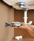 User holding a Dremel tool under a sink, using the Total Game Changer Multipurpose Cutting Kit for precise cuts.