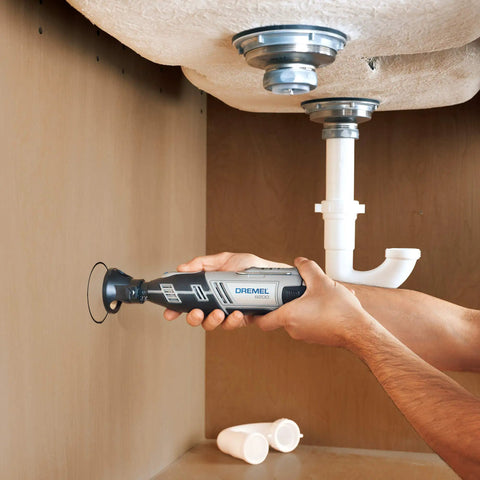 User holding a Dremel tool under a sink, using the Total Game Changer Multipurpose Cutting Kit for precise cuts.