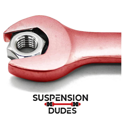 Close-up of a red wrench holding a metal nut with Suspension Dudes logo below.