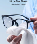 Close-up of white microfiber cleaning cloth wiping black eyeglasses (6 x 6 in).