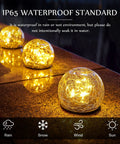 Solar Globe Lights 6 Inch Outdoor Crackled Glass Orbs glowing warmly on a patio, showcasing waterproof design.