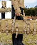 Person carrying a tan tactical gear bag with multiple compartments and buckles, outdoor shooting range in background.