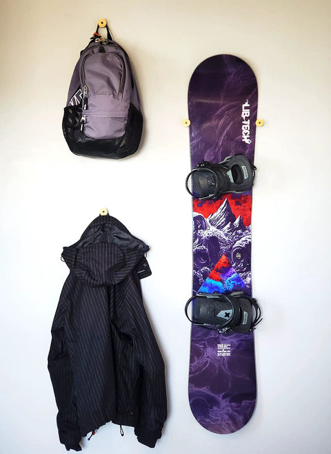 Keep Your Winter Setup Clean With These Sick Bamboo Flush Ski Wall Mount And Snowboard Rack Solutions Solid Space Saving Storage That Holds Boards Flat Against The Wall While You Rip with a snowboard, jacket, and backpack on wall.