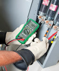 Electrician using Pro Grade Digital Multimeter DM45 600V AC DC, 10A Auto Range, Capacitance And Temperature Testing on panel.