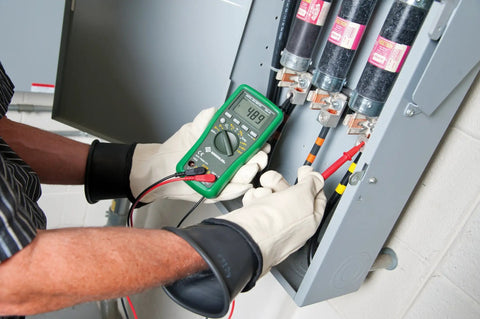Electrician using Pro Grade Digital Multimeter DM45 600V AC DC, 10A Auto Range, Capacitance And Temperature Testing on panel.