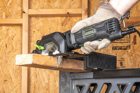 Genesis Mini Circular Saw 4.0 Amp 4-1/2 Inch with 24-Tooth Carbide Blade making plunge cut in wood, held with one hand