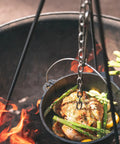 Rugged Heavy Duty Steel Camping Tripod For Open Fire Cooking suspends Dutch oven over flames with chicken and asparagus