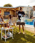 Outdoor barbecue scene with Mobile 30 By 24 Inch NSF Stainless Steel Workbench With Four Wheels And Hooks by a pool.