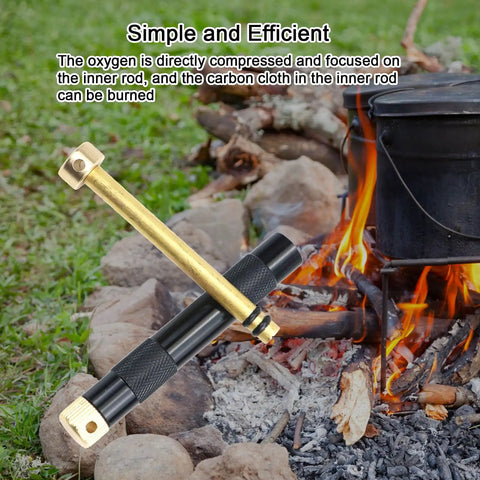 Compact Air Compression Fire Starter With Durable Metal Body next to campfire and cooking pot outdoors.